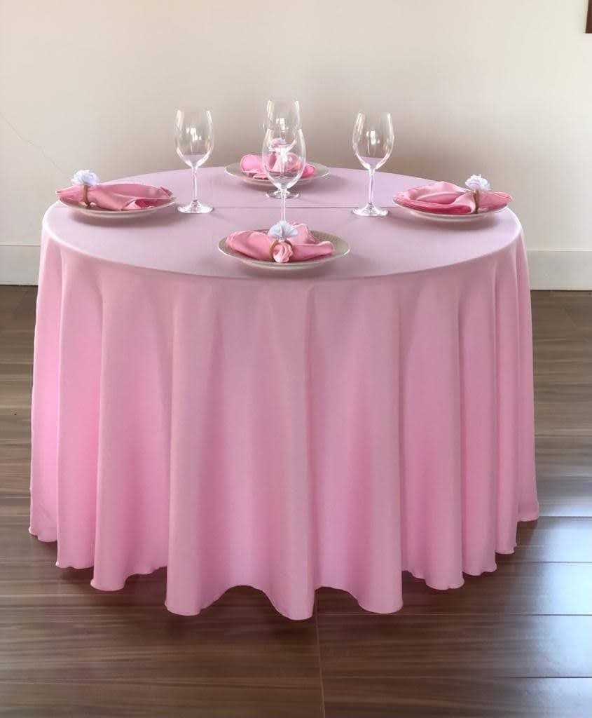 Mesa redonda com toalha rosa longa e composição de festa